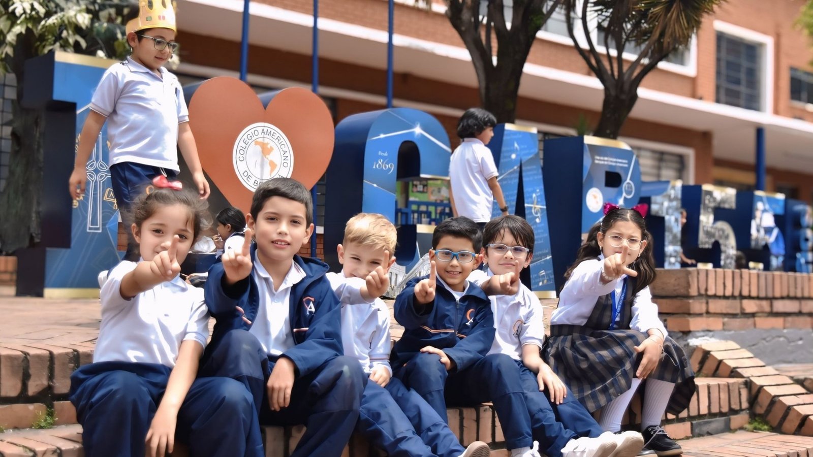 Estudiantes del Colegio Americano de Bogotá frente al letrero del colegio